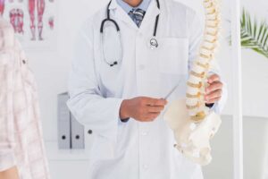 A chiropractor adjusts an adult patient’s back in a bright, calm clinic room.