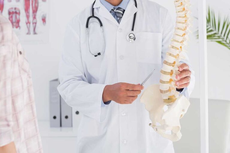 A chiropractor adjusts an adult patient’s back in a bright, calm clinic room.
