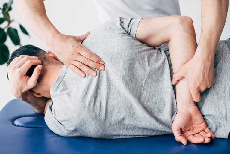 Chiropractor reviewing a spine diagram with a patient in a bright examination room.